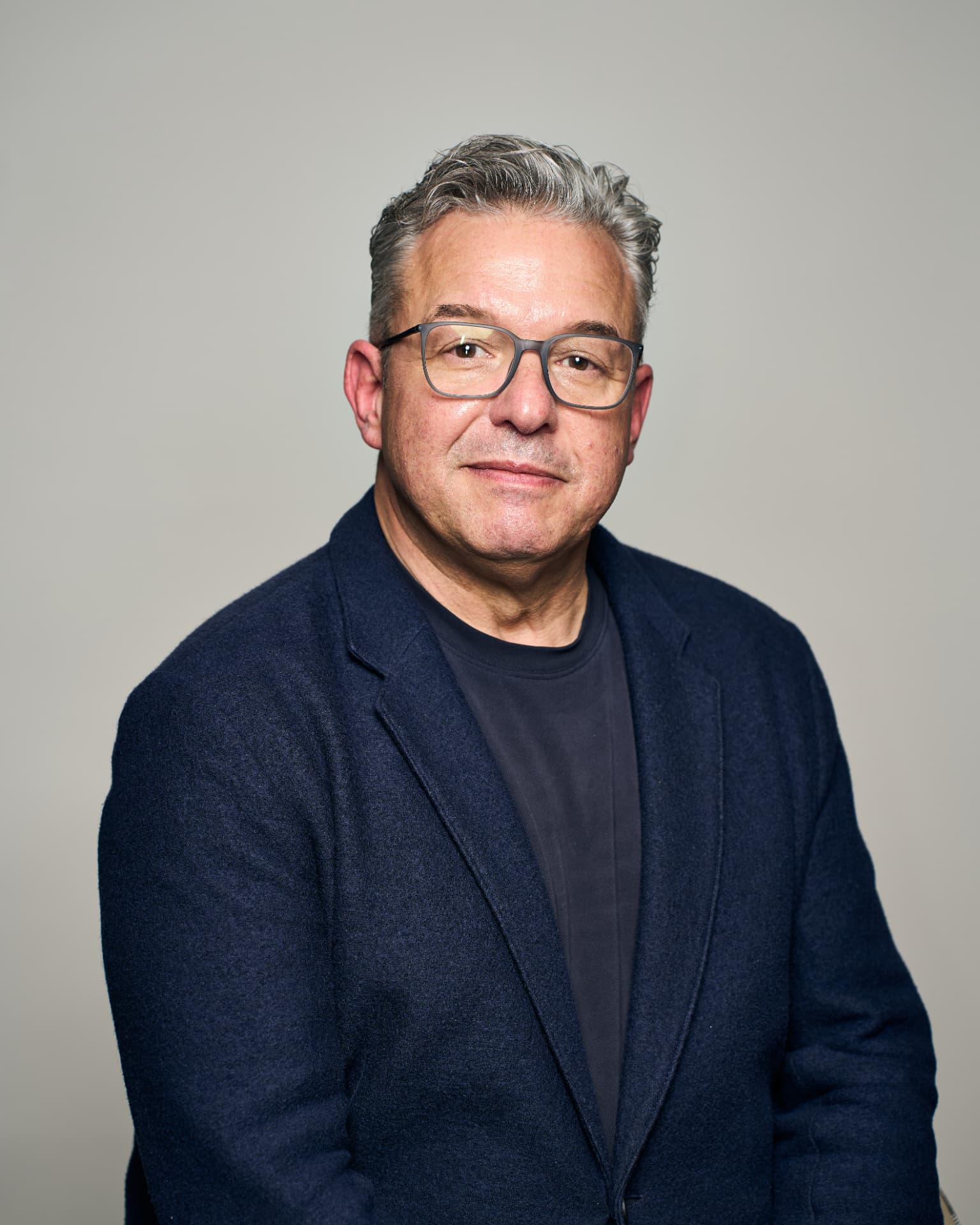 Zakelijk portret van een man met bril tegen een neutrale achtergrond