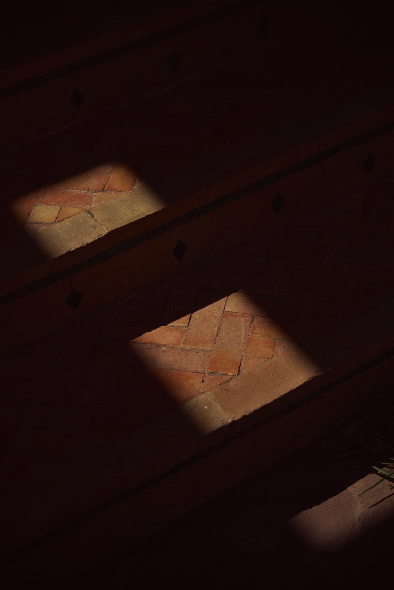 Two bands of sunlight across terracotta herringbone steps