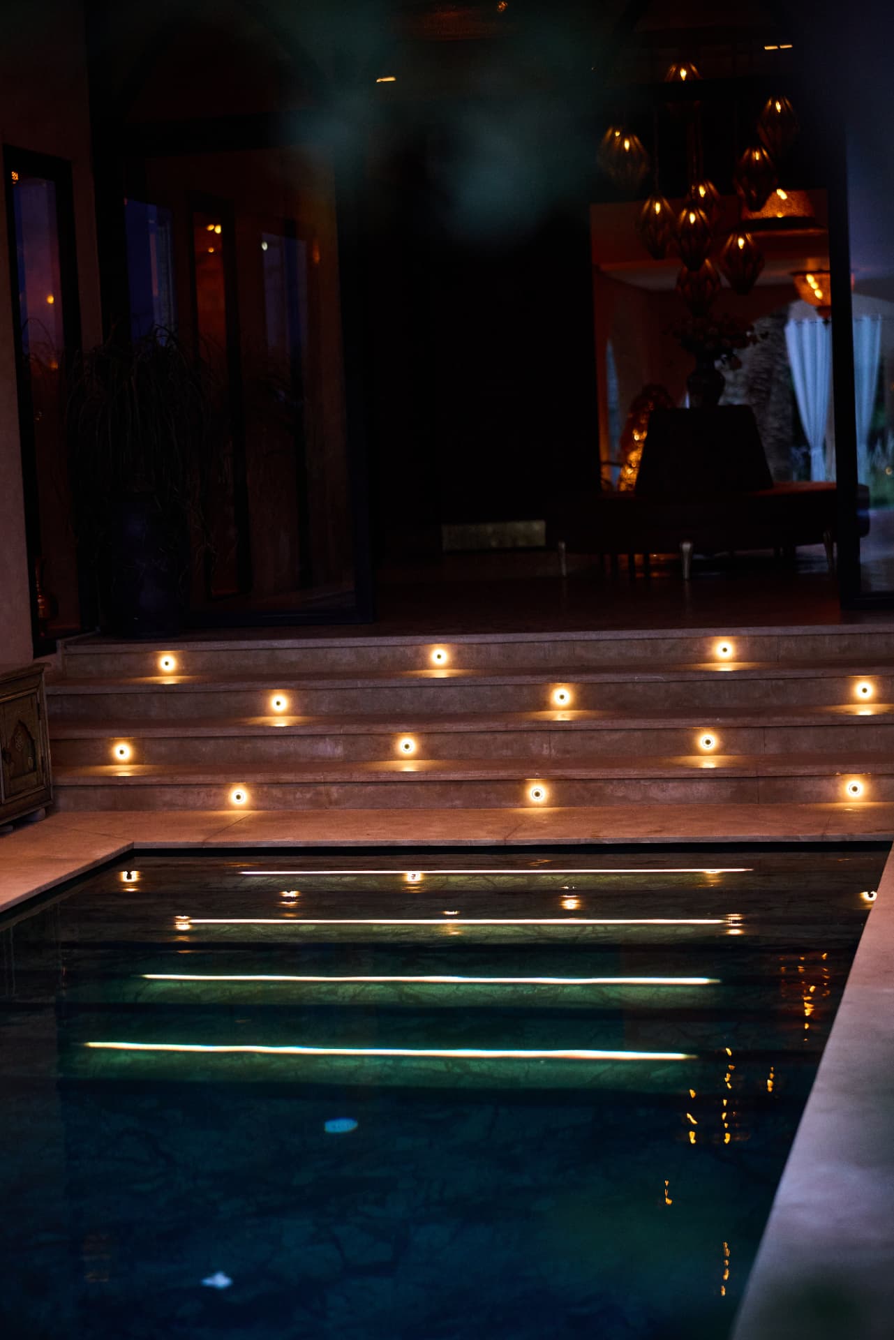 Candles lining the steps of the pool at night