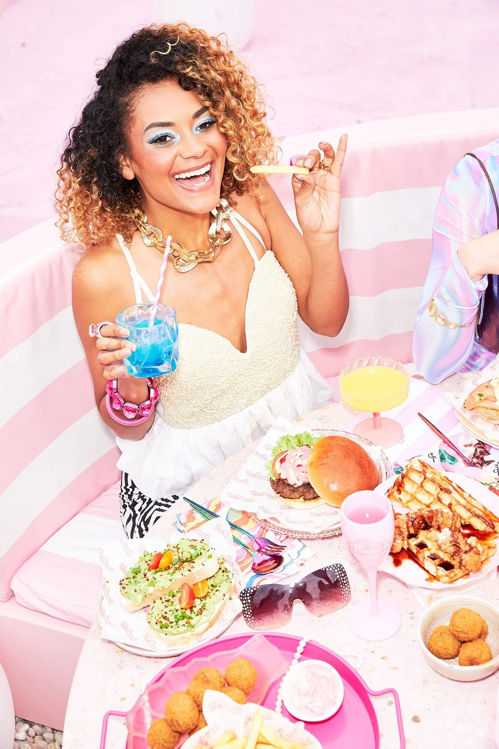 Woman with a blue drink at a pink brunch table