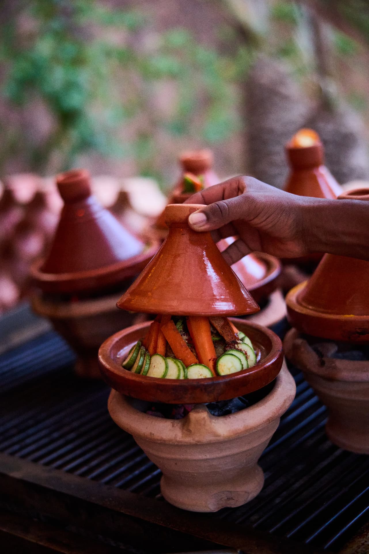 Hand lifting the lid of a vegetable tagine