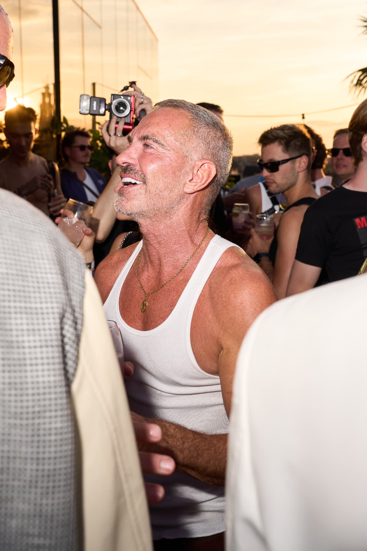 Dean Caten laughing in the rooftop crowd at golden hour