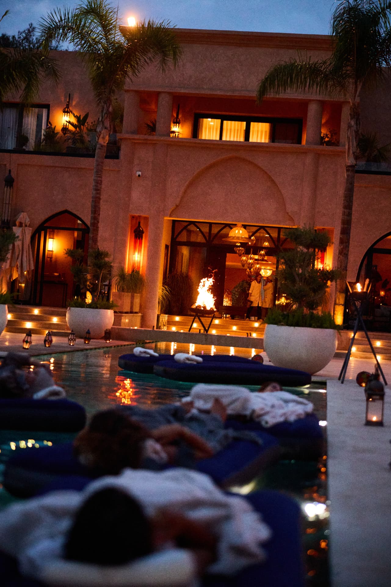Guests wrapped in blankets by the illuminated pool