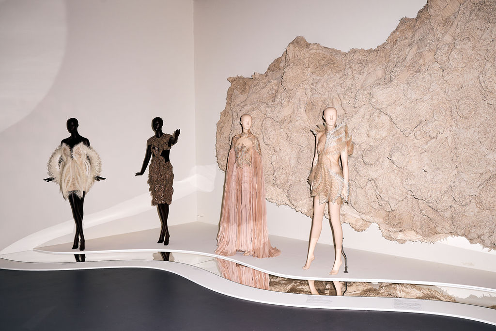 Pale couture gowns beside a sculpted coral wall