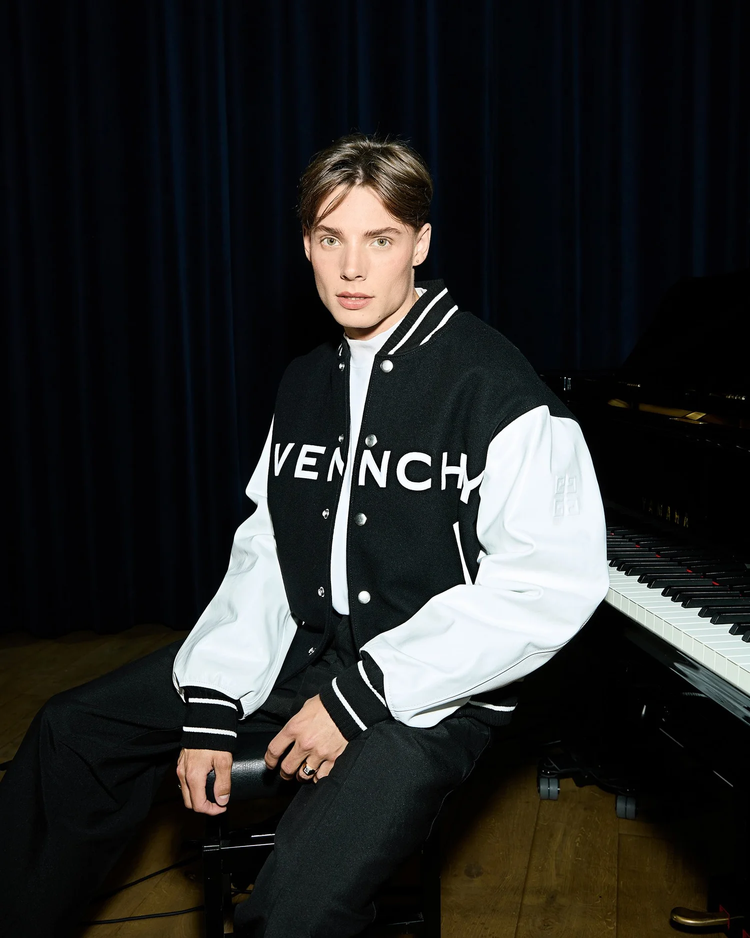 Portrait of Dim in a varsity jacket seated at a grand piano