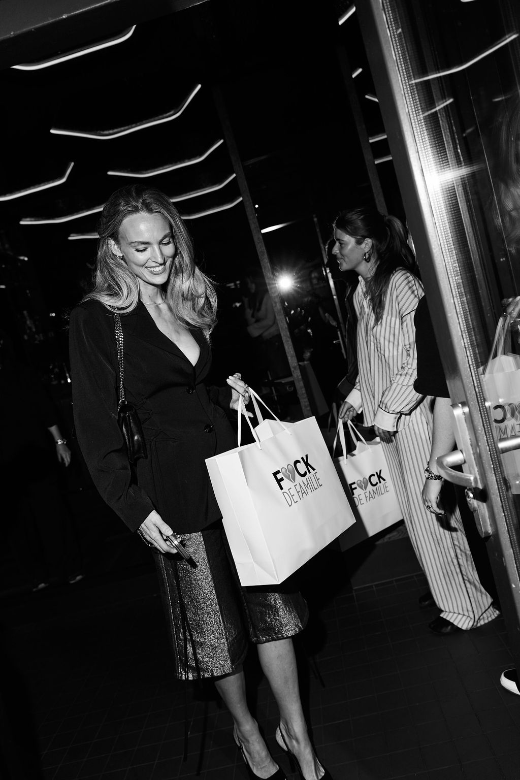 Guest walking out with a F*ck de Familie goodie bag, black and white