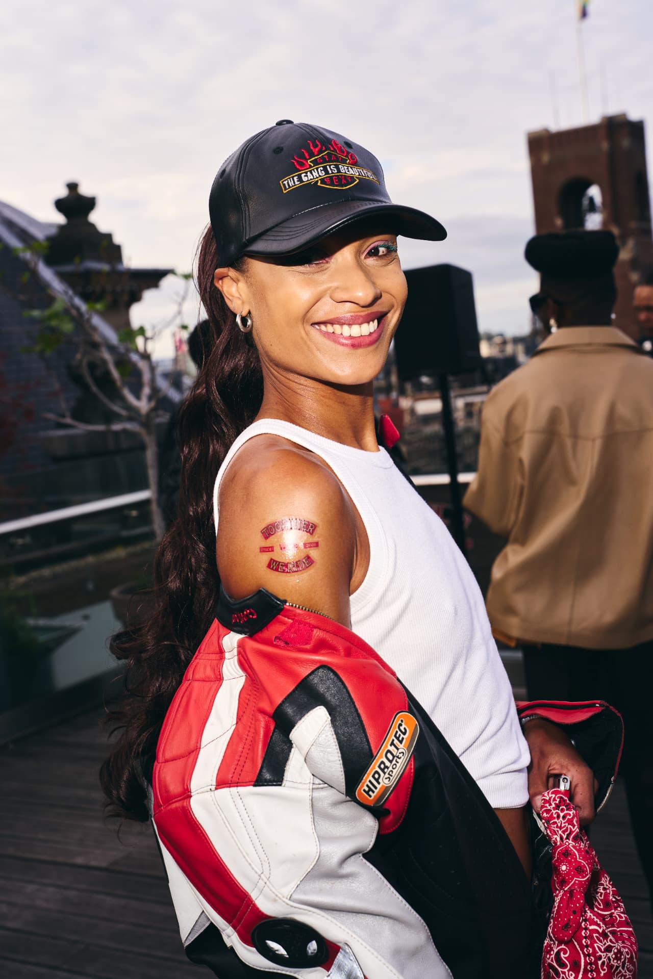 Guest in a leather cap smiling with a Together We Ride tattoo on her arm