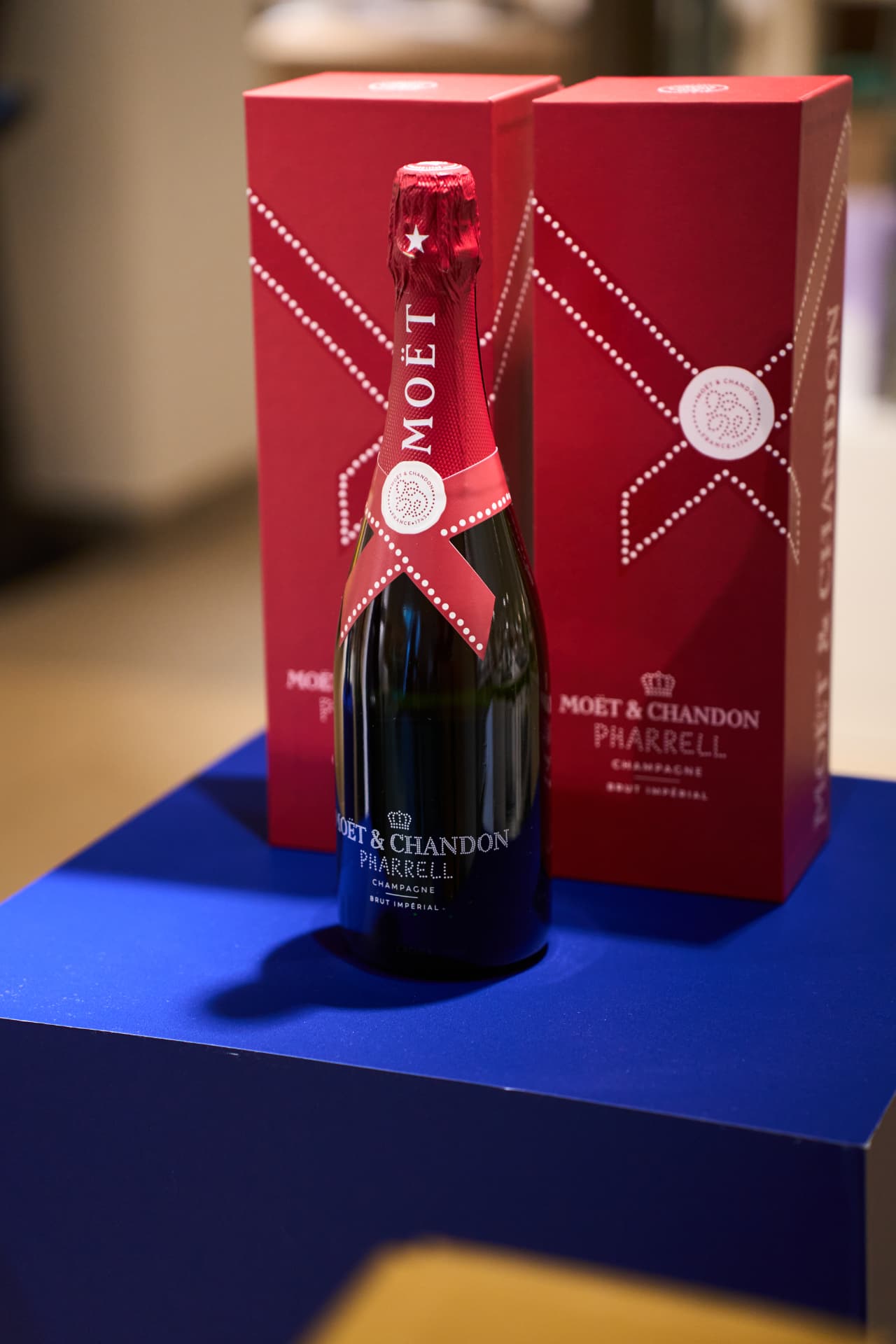 Bottle and red gift boxes on a blue plinth