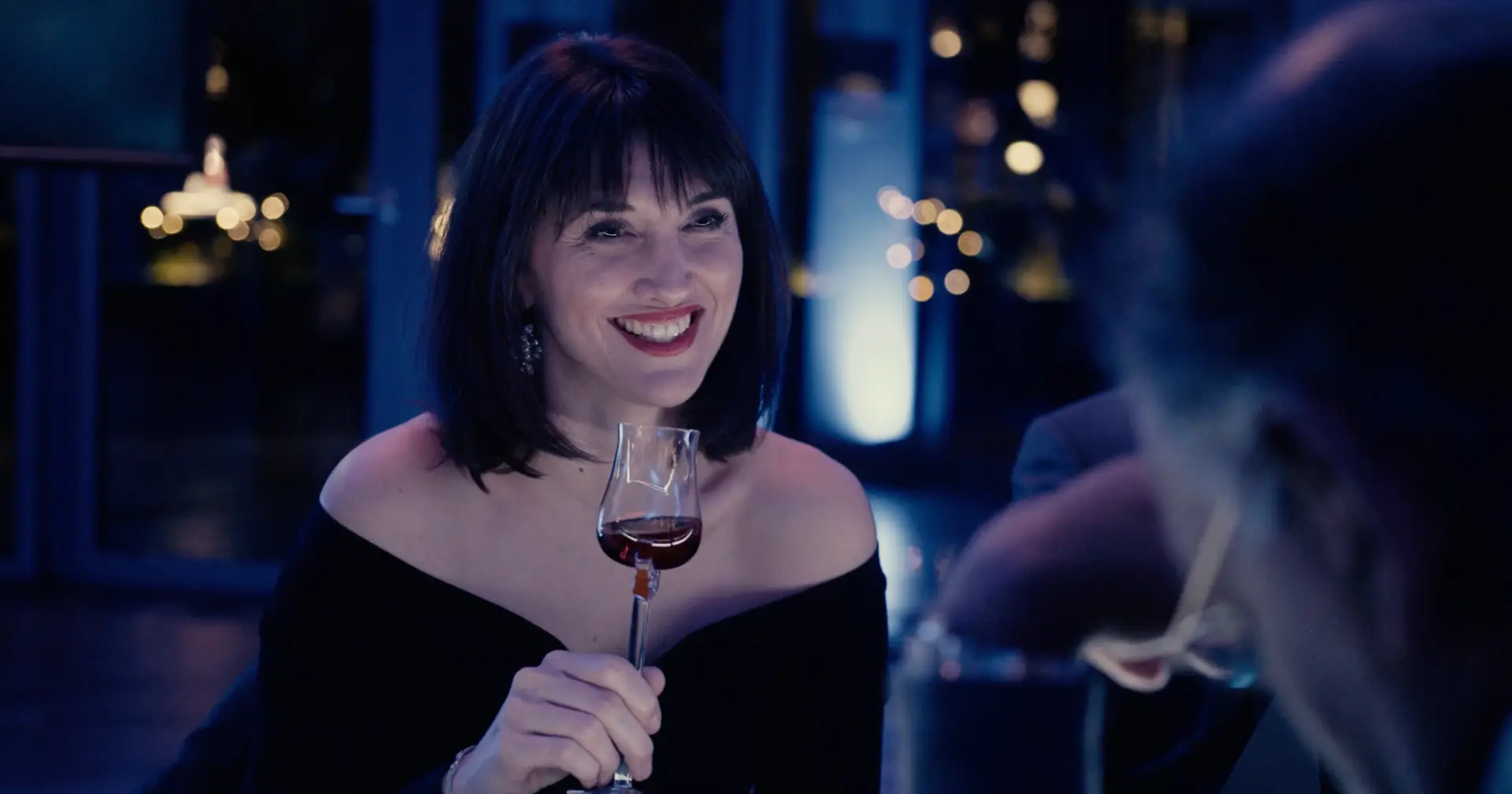 Guest smiling with a tasting glass at dinner