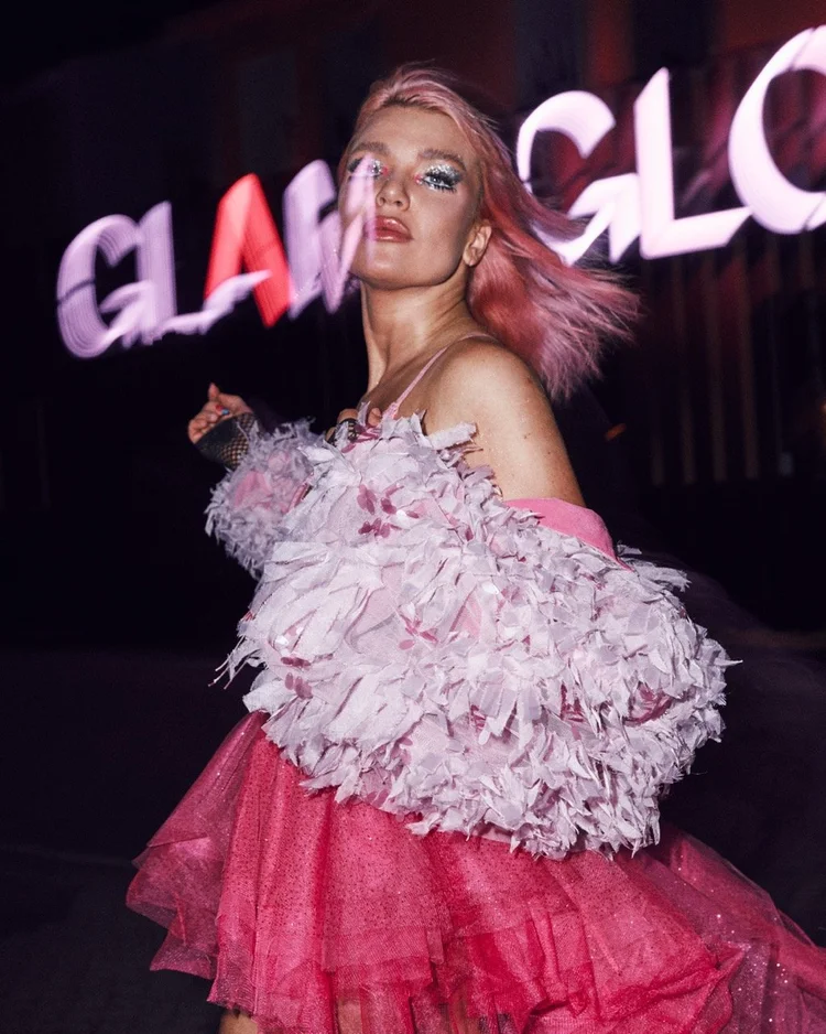 Model in ruffles in front of a neon sign at night