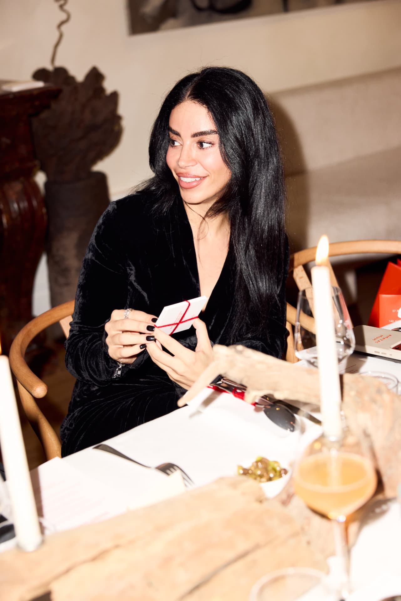 Guest writing on a question card at the candlelit dinner table