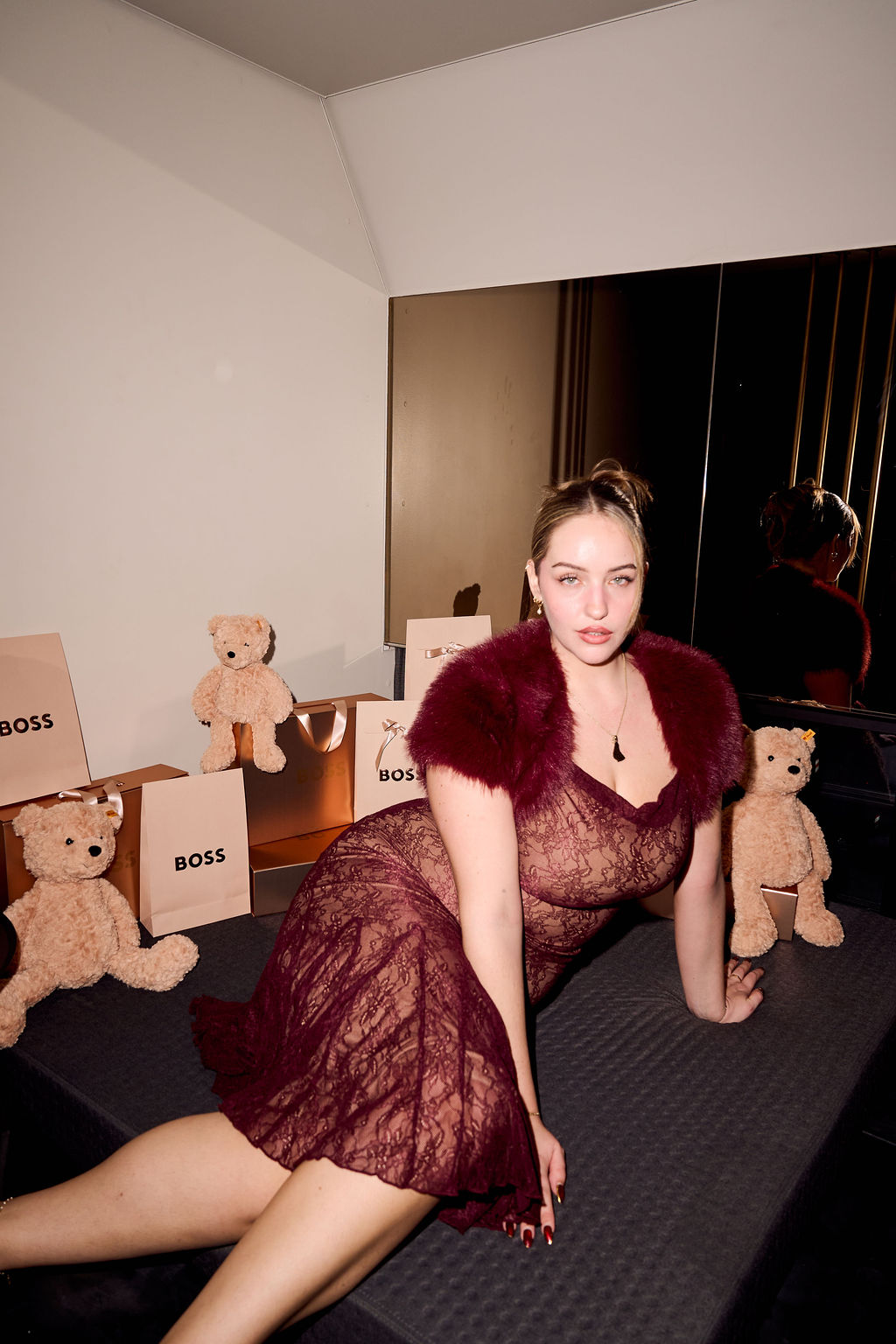 Guest in burgundy lace surrounded by BOSS bags and teddy bears