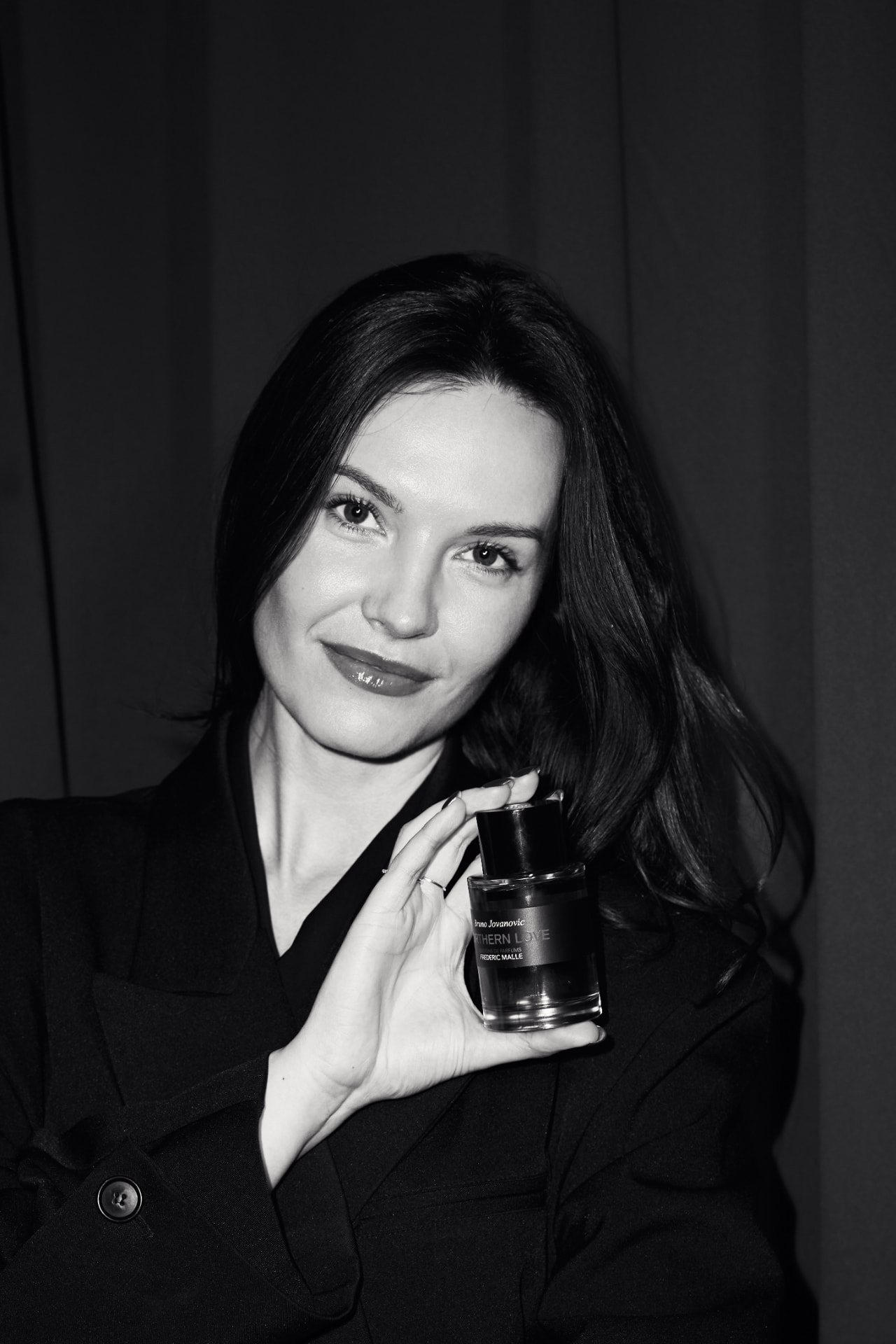 Black and white portrait of a guest with a Frederic Malle bottle