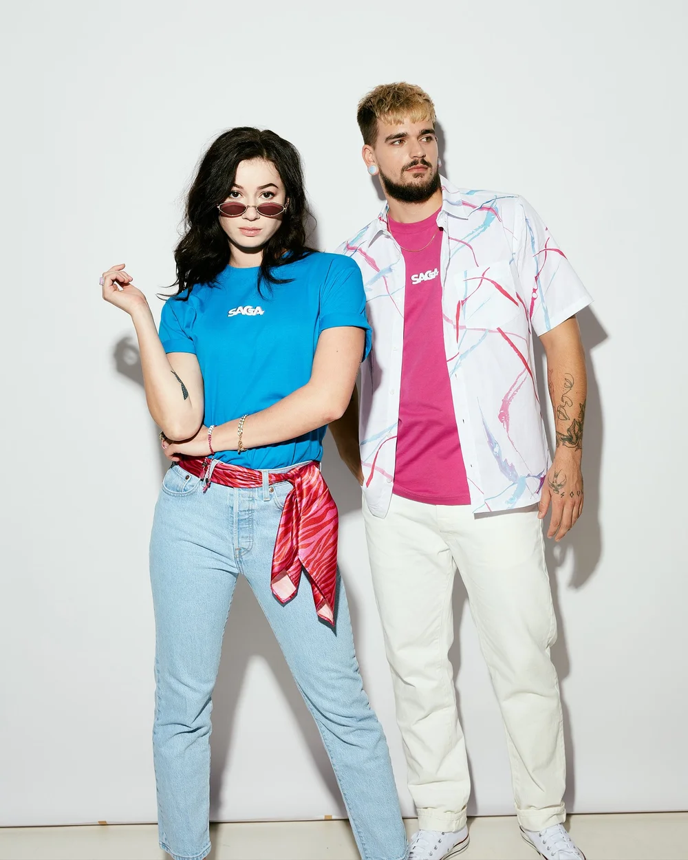 Two models in SAGA tees against a white studio wall