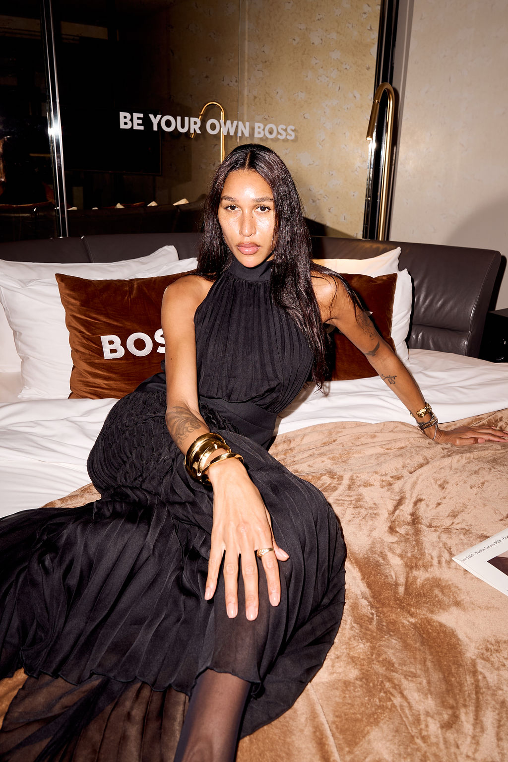 Guest in a black dress on the bed between BOSS pillows