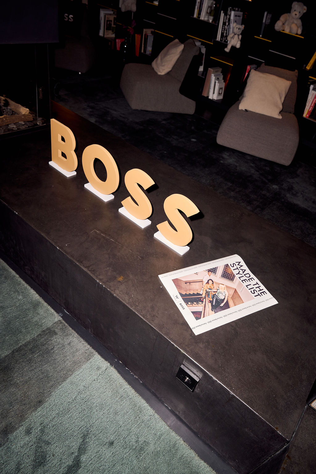 BOSS letters standing on a dark surface beside a magazine