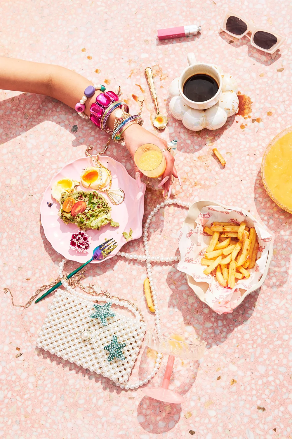 Flat lay of avocado toast, fries, coffee and a pearl bag