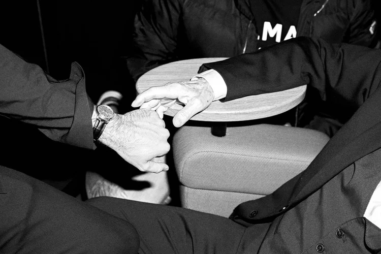 Two hands meeting in the back of a car, black and white