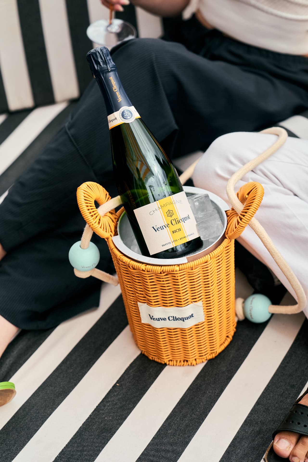 Wicker cooler with a bottle on a striped daybed