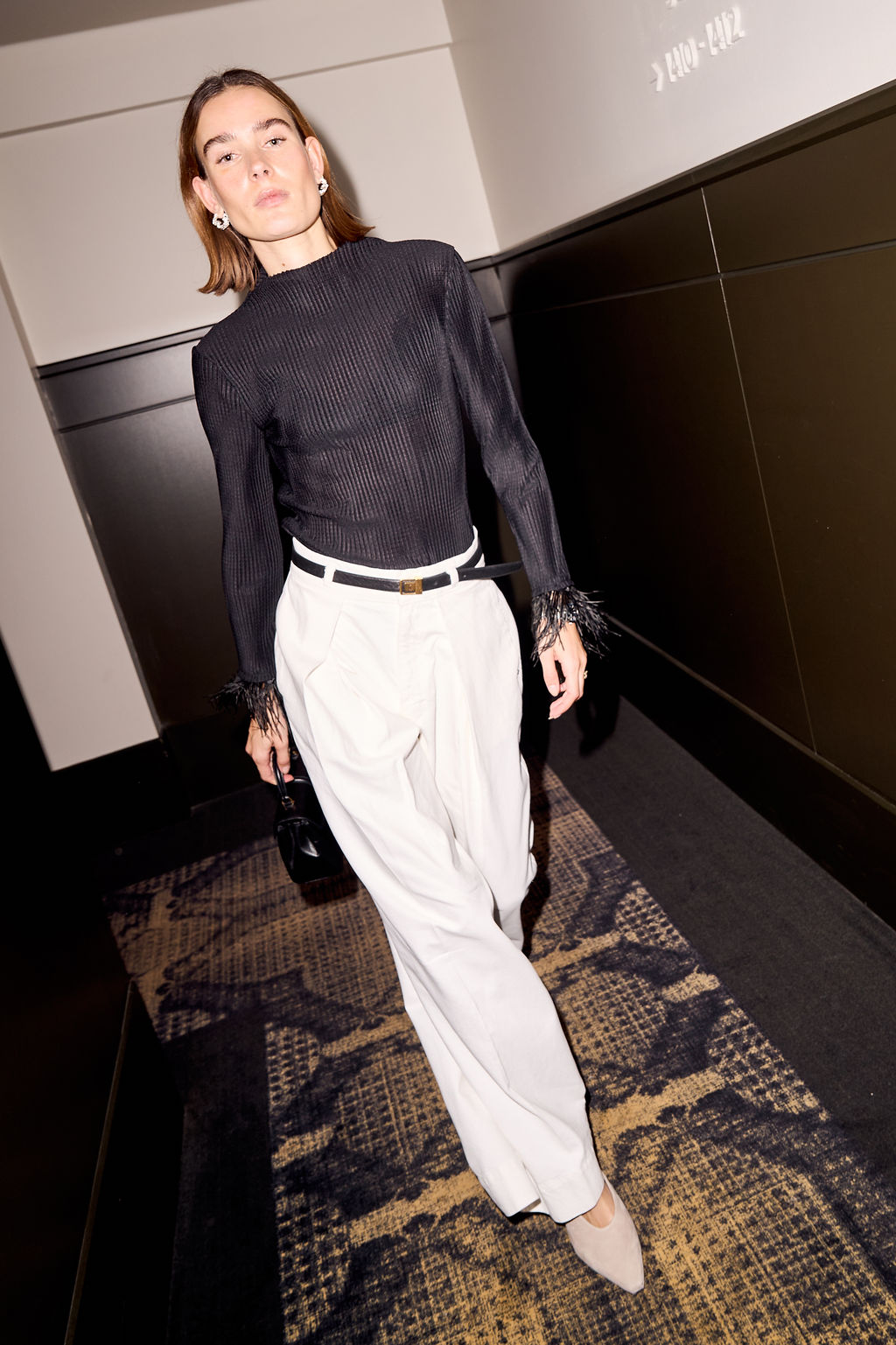 Guest walking the hotel corridor in a black knit