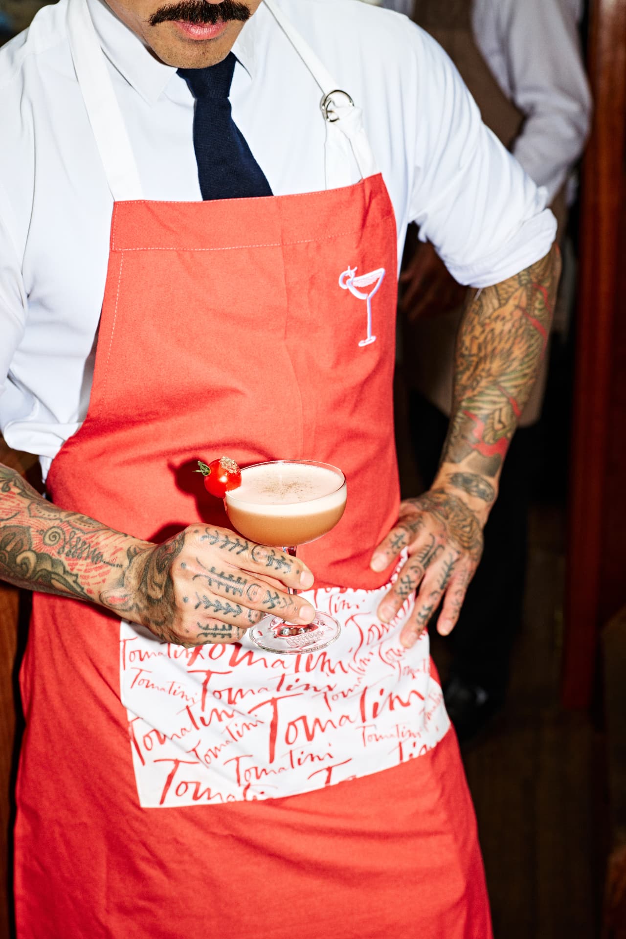 Bartender in a red apron holding a Ketel One cocktail