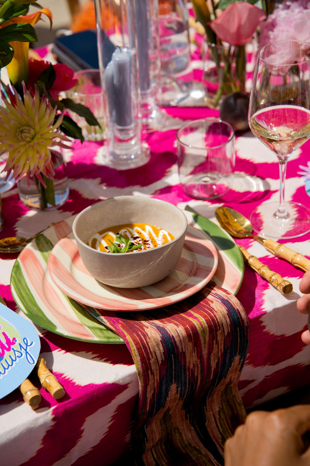 Bowl of soup on a striped plate on the pink table