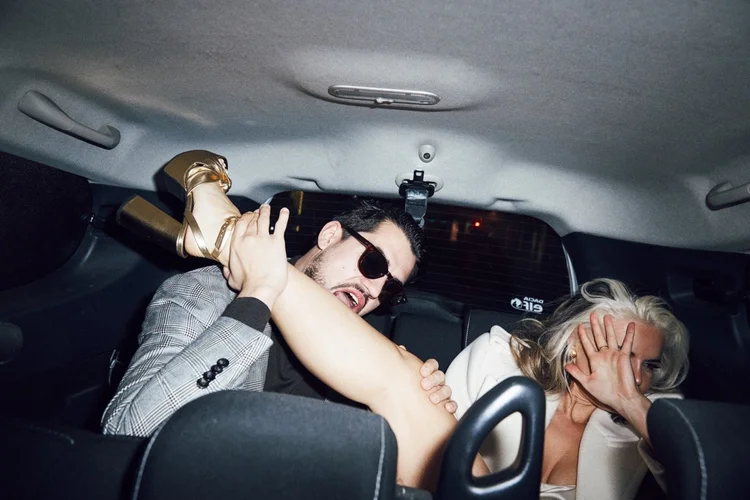 Two people piled into the back of a taxi at night