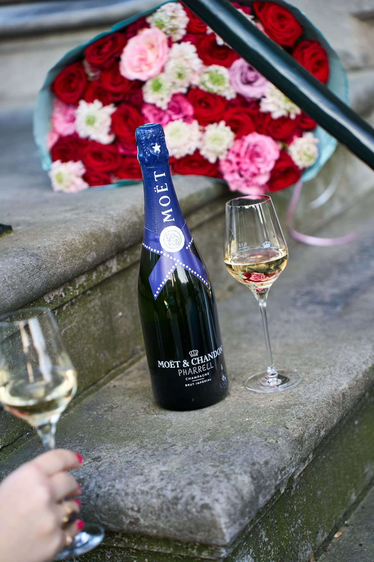 Bottle and glasses on the stoop beside roses