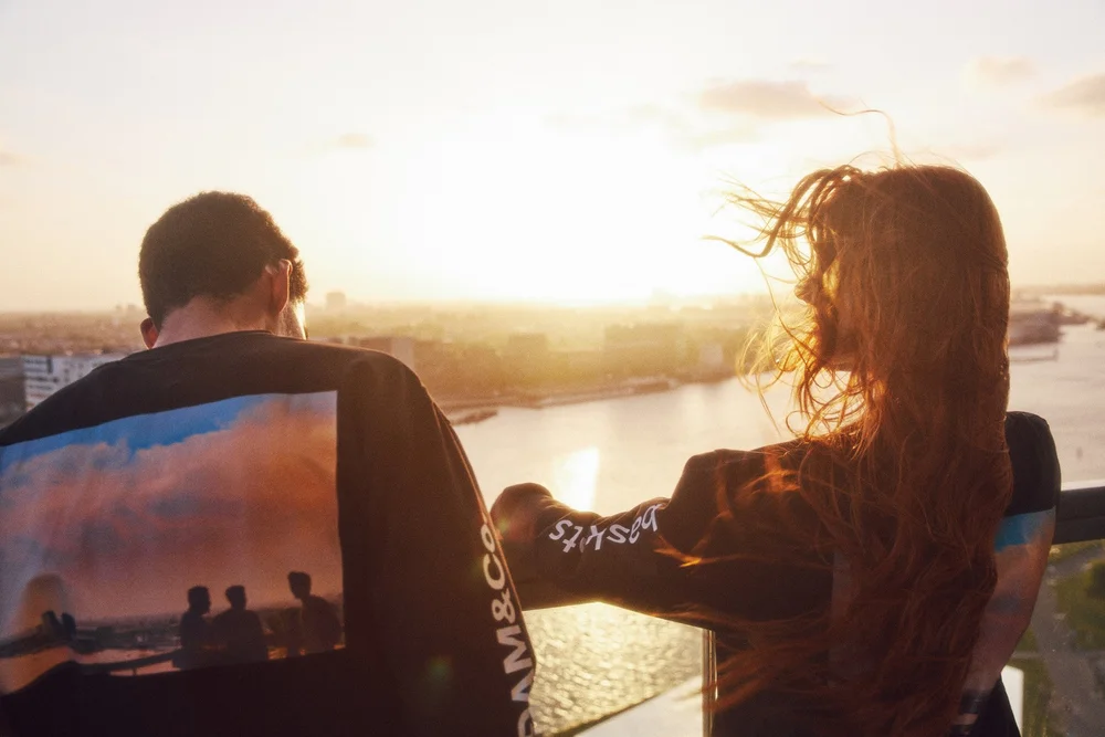 Two models from behind looking out over Amsterdam at sunset