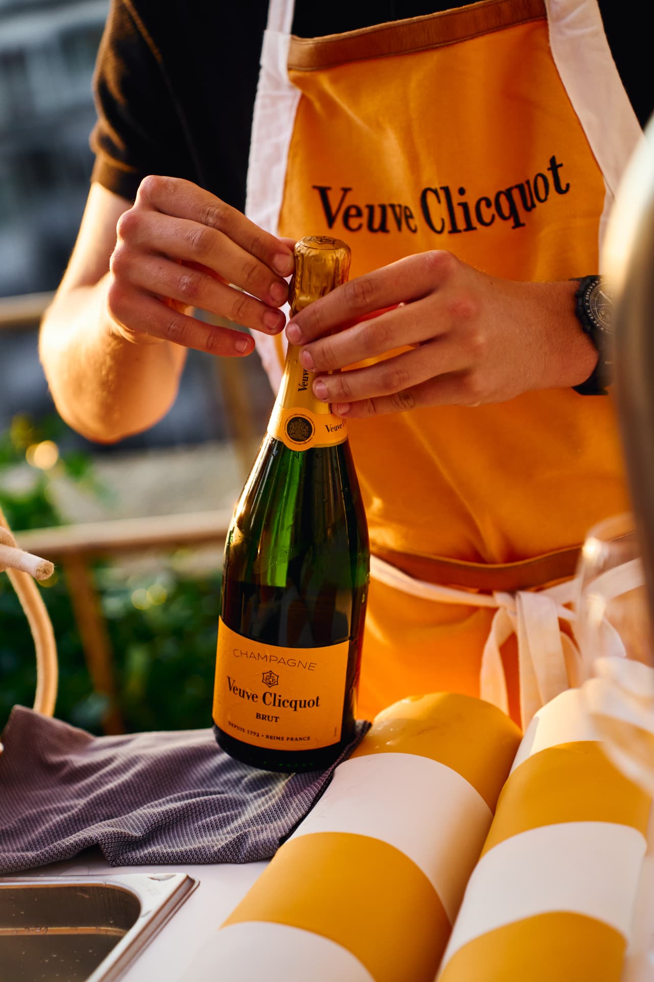 Server in a branded apron opening a bottle