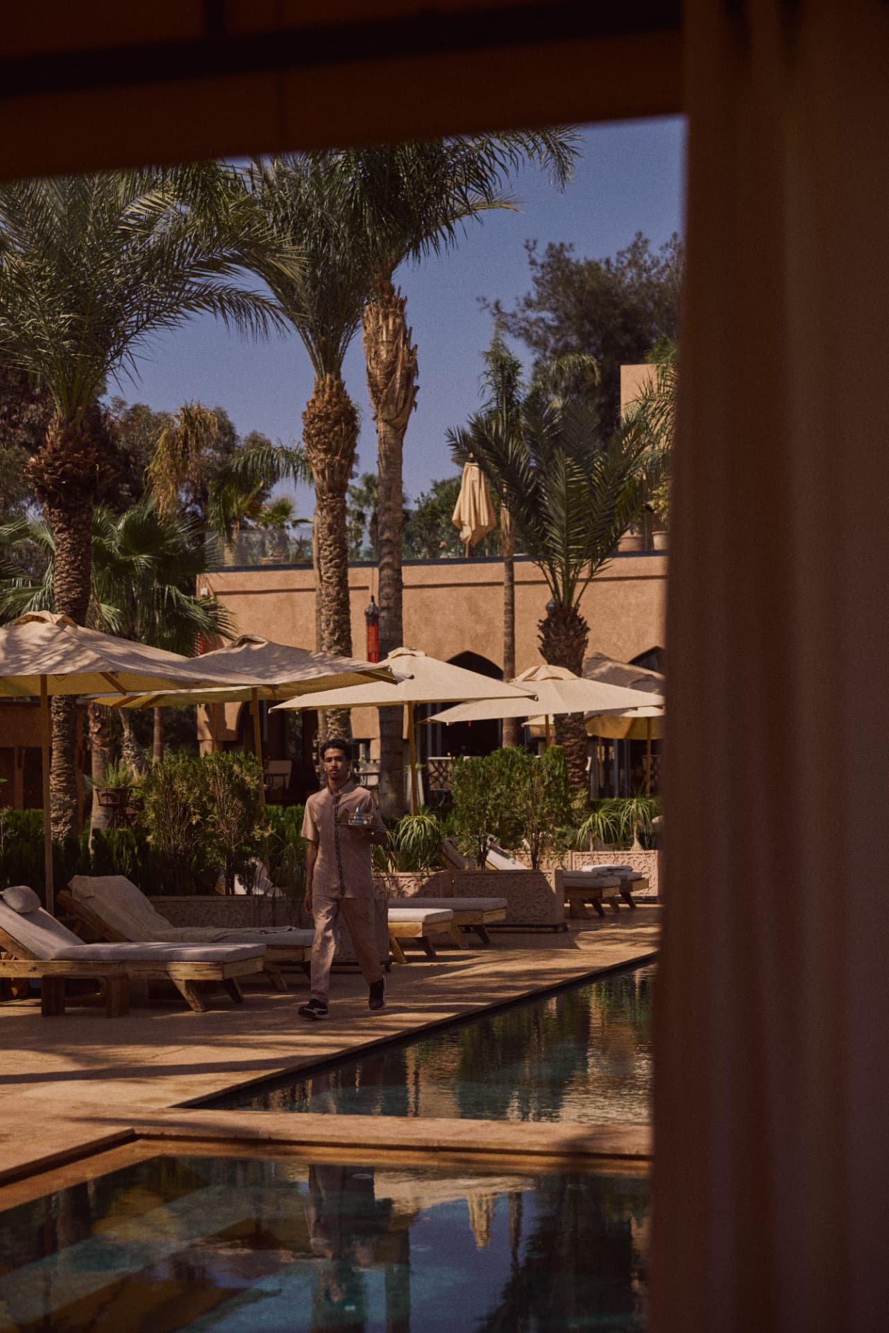 Waiter walking along the pool past the loungers