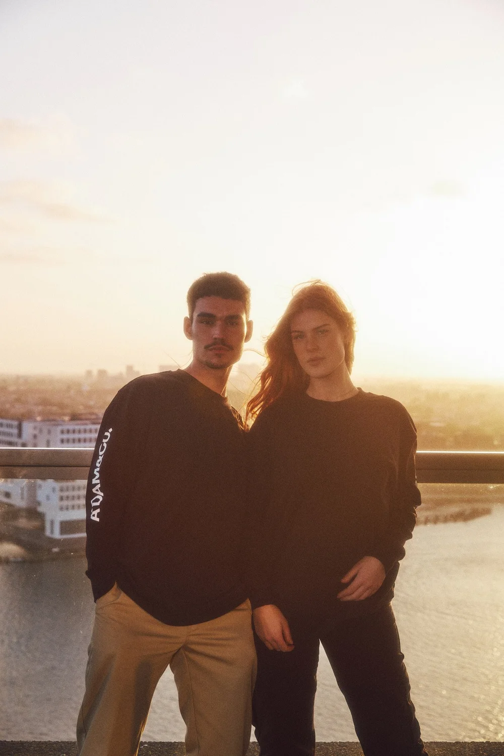 Two models standing close together against the setting sun