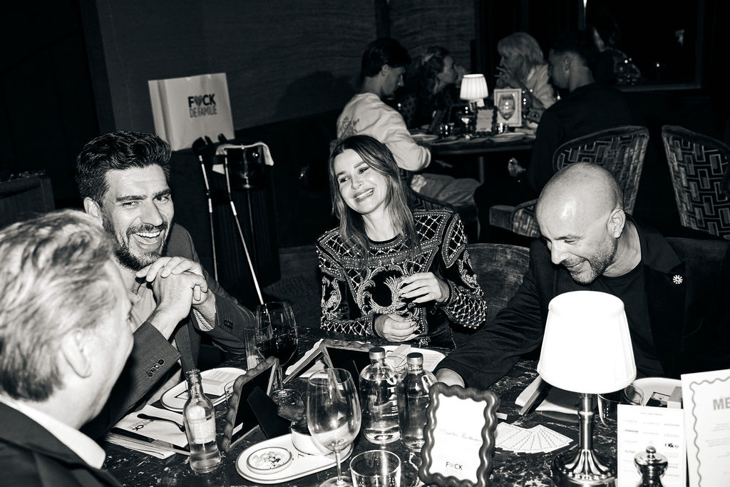 Victoria Koblenko laughing with guests at the dinner table in black and white
