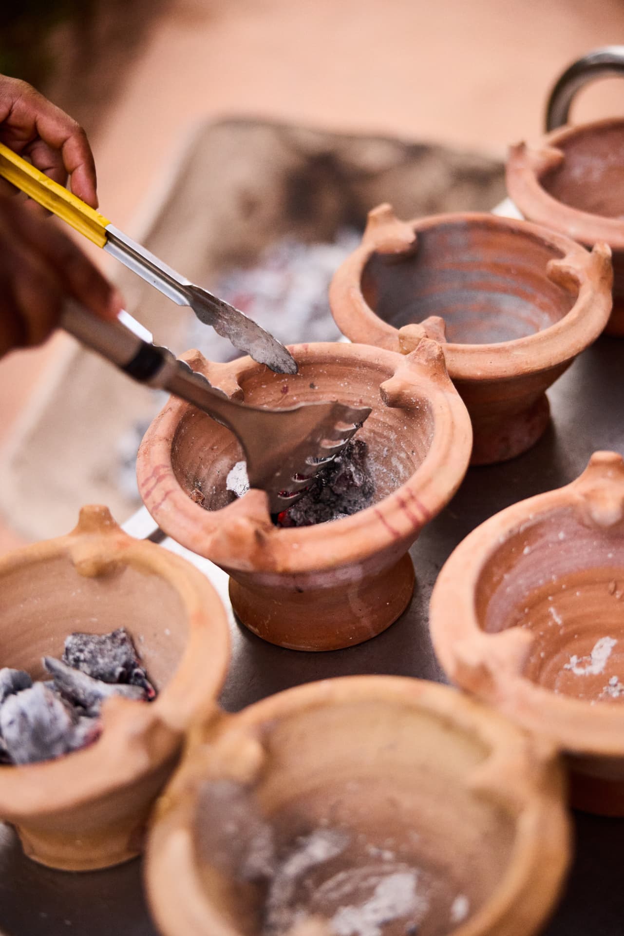 Glowing charcoal being placed in clay pots