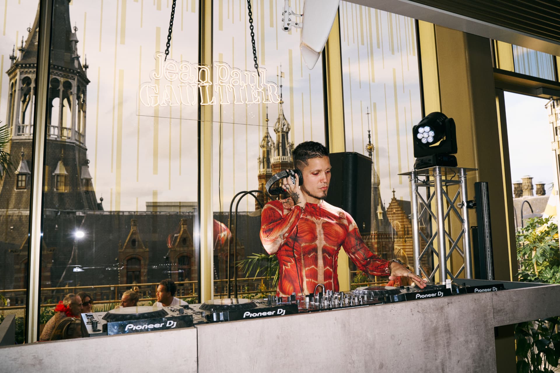DJ in a muscle print shirt under the Gaultier neon sign