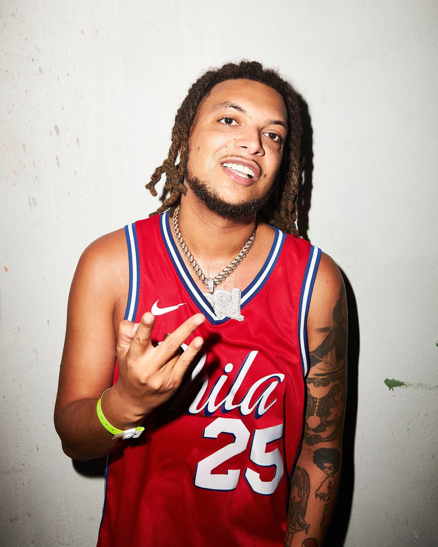 Ronnie Flex in a red basketball jersey against a scuffed wall