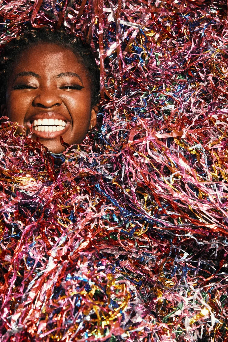 Portrait laughing inside a bed of metallic confetti
