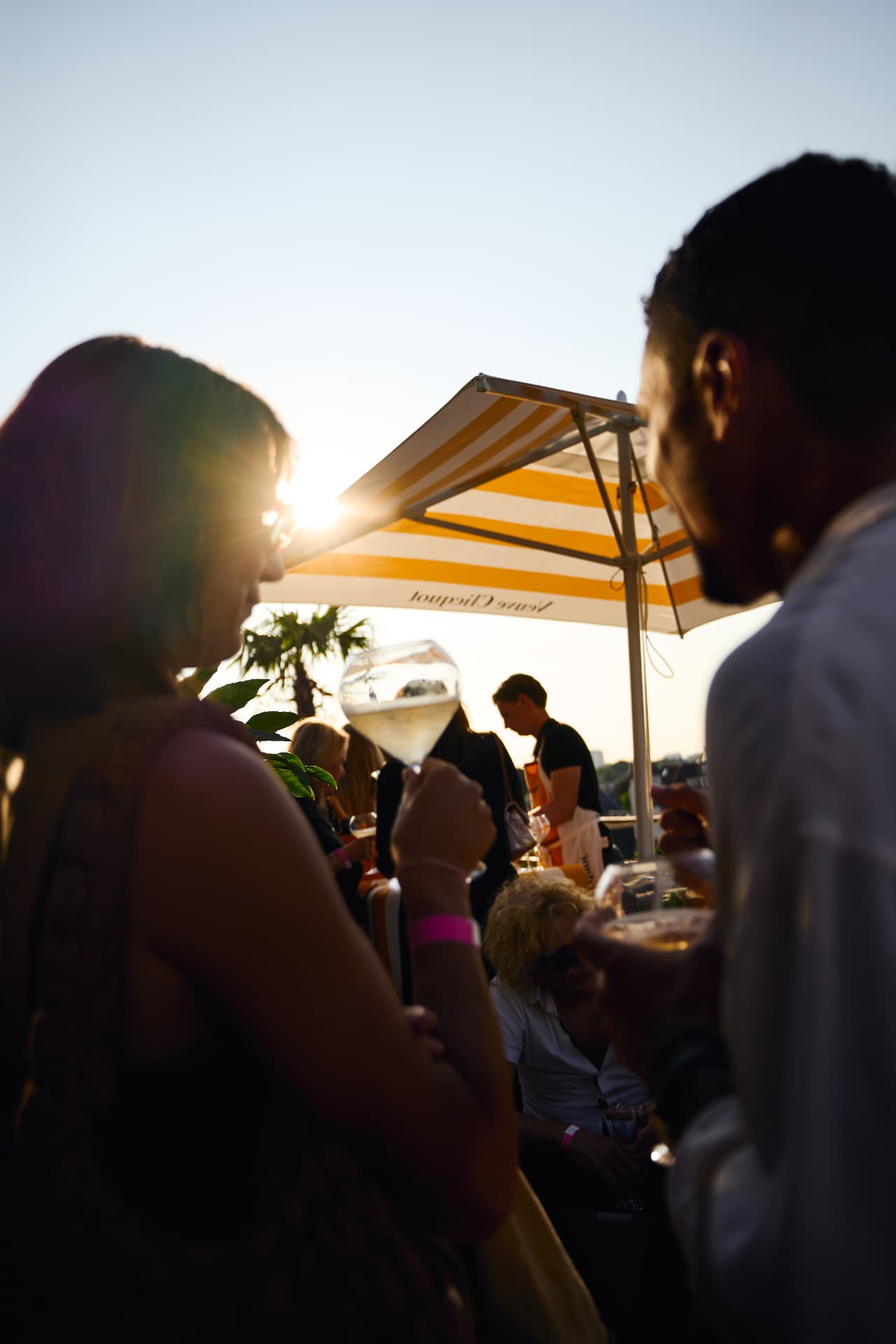 Guests with drinks on the sunlit rooftop