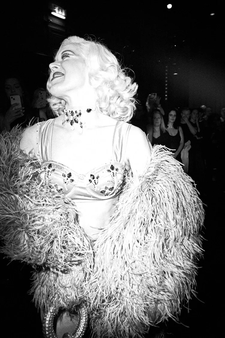 Performer in feathers and crystals under a spotlight, black and white