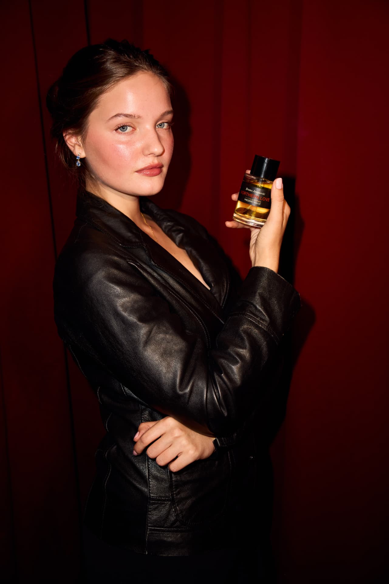 Guest in a leather jacket holding Northern Love against the red curtain