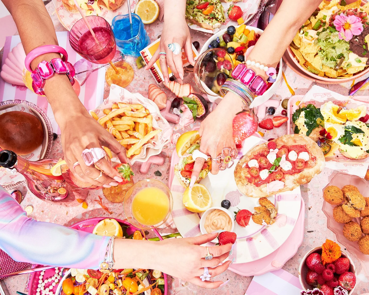 Overhead of many hands reaching across a full brunch table
