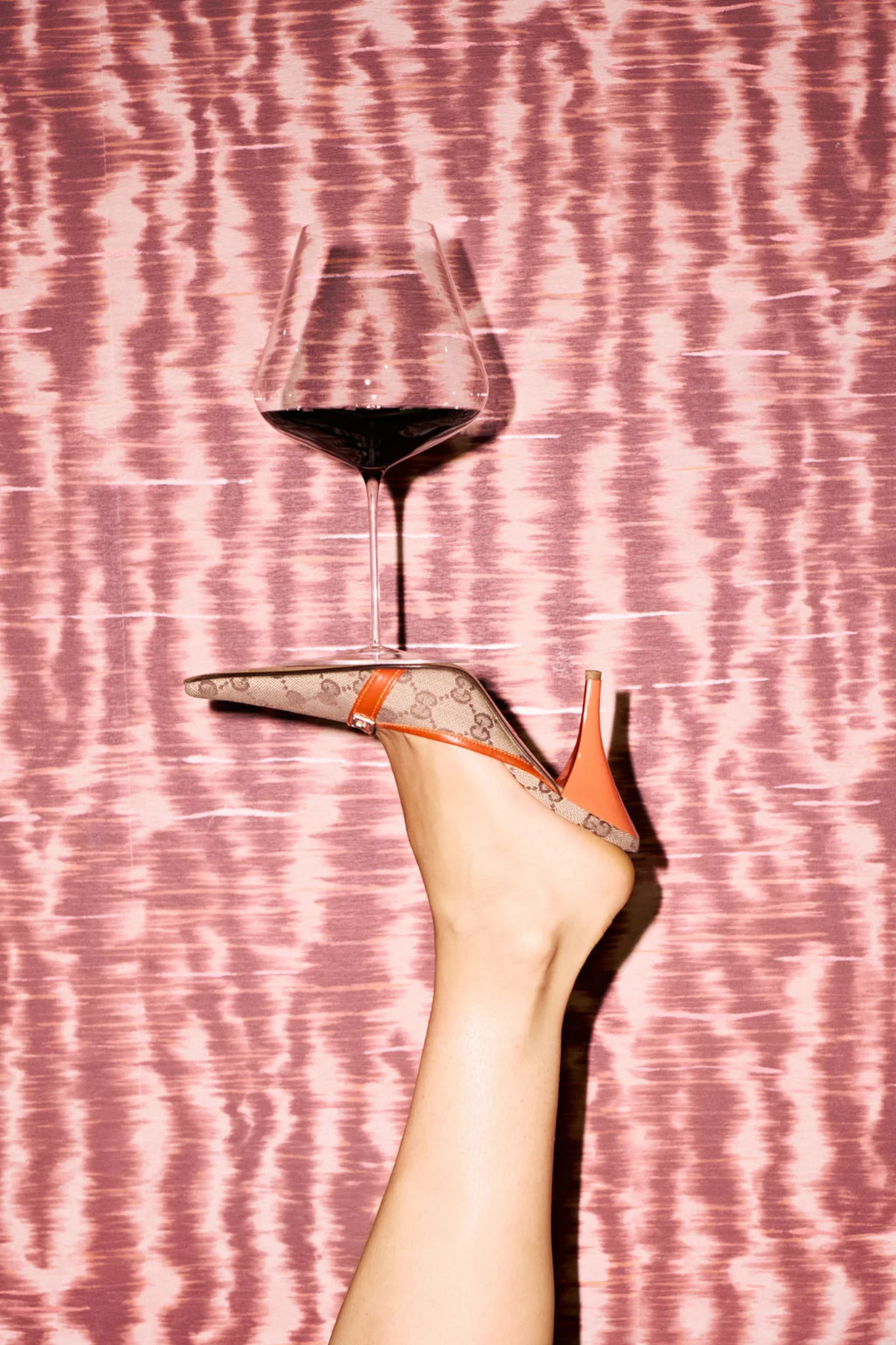 Red wine glass against a pink textured backdrop