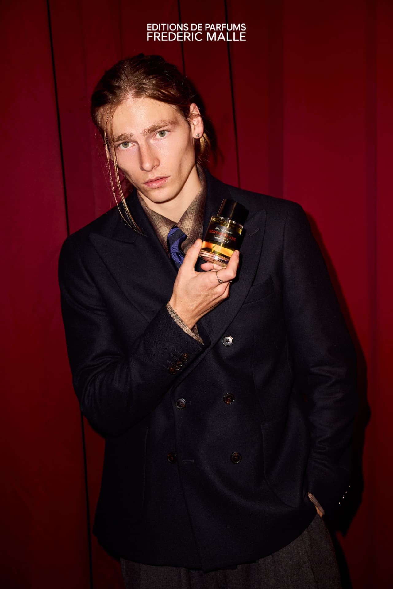 Guest holding Northern Love in front of the red Frederic Malle curtain