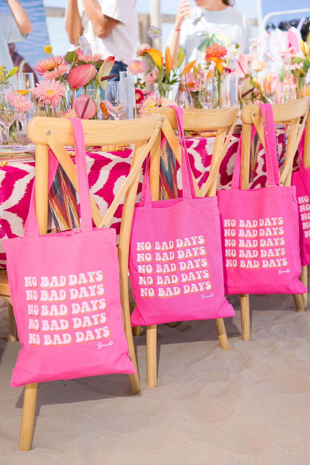 Pink No Bad Days totes hung on wooden chairs