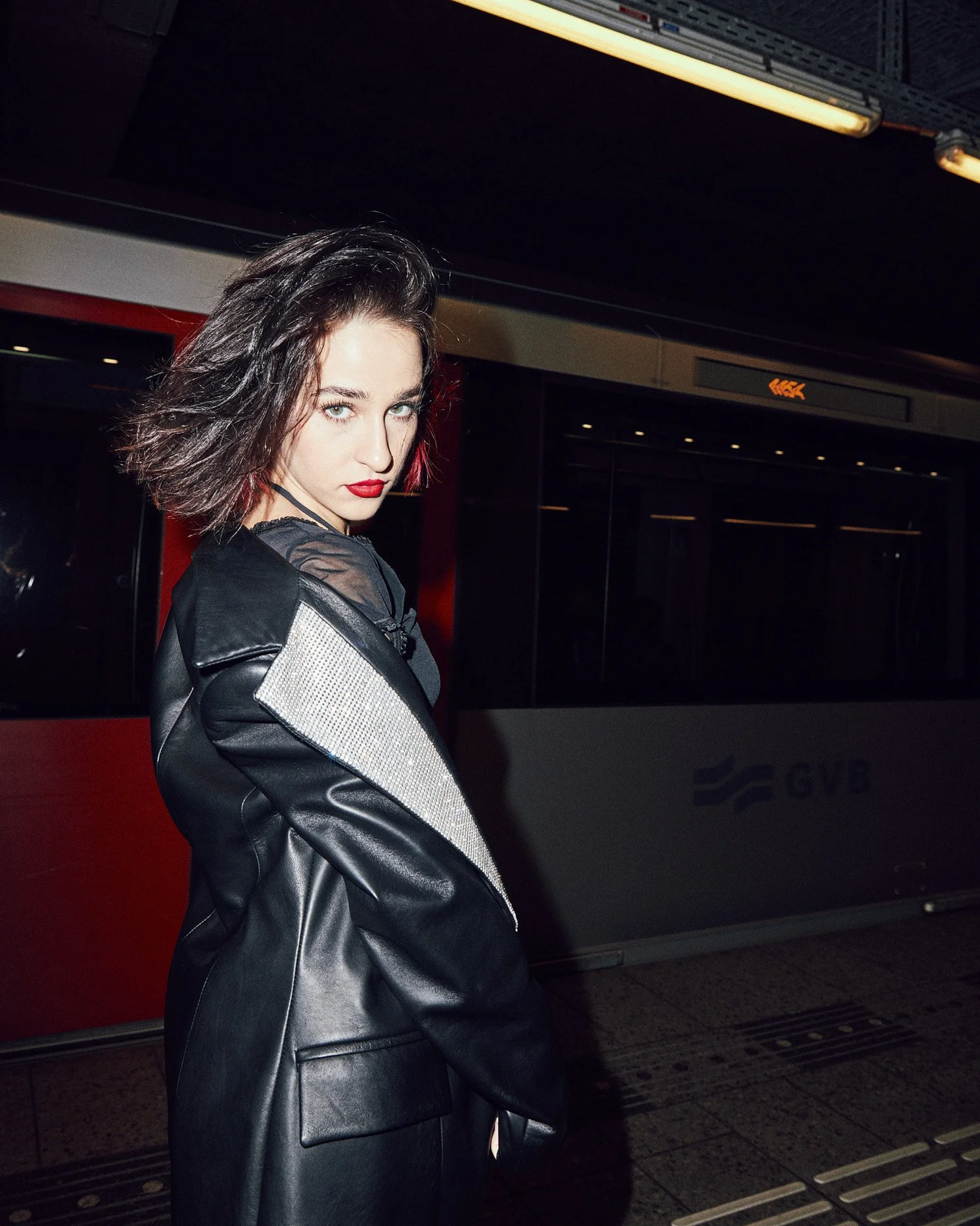 Model in a leather coat on a metro platform at night