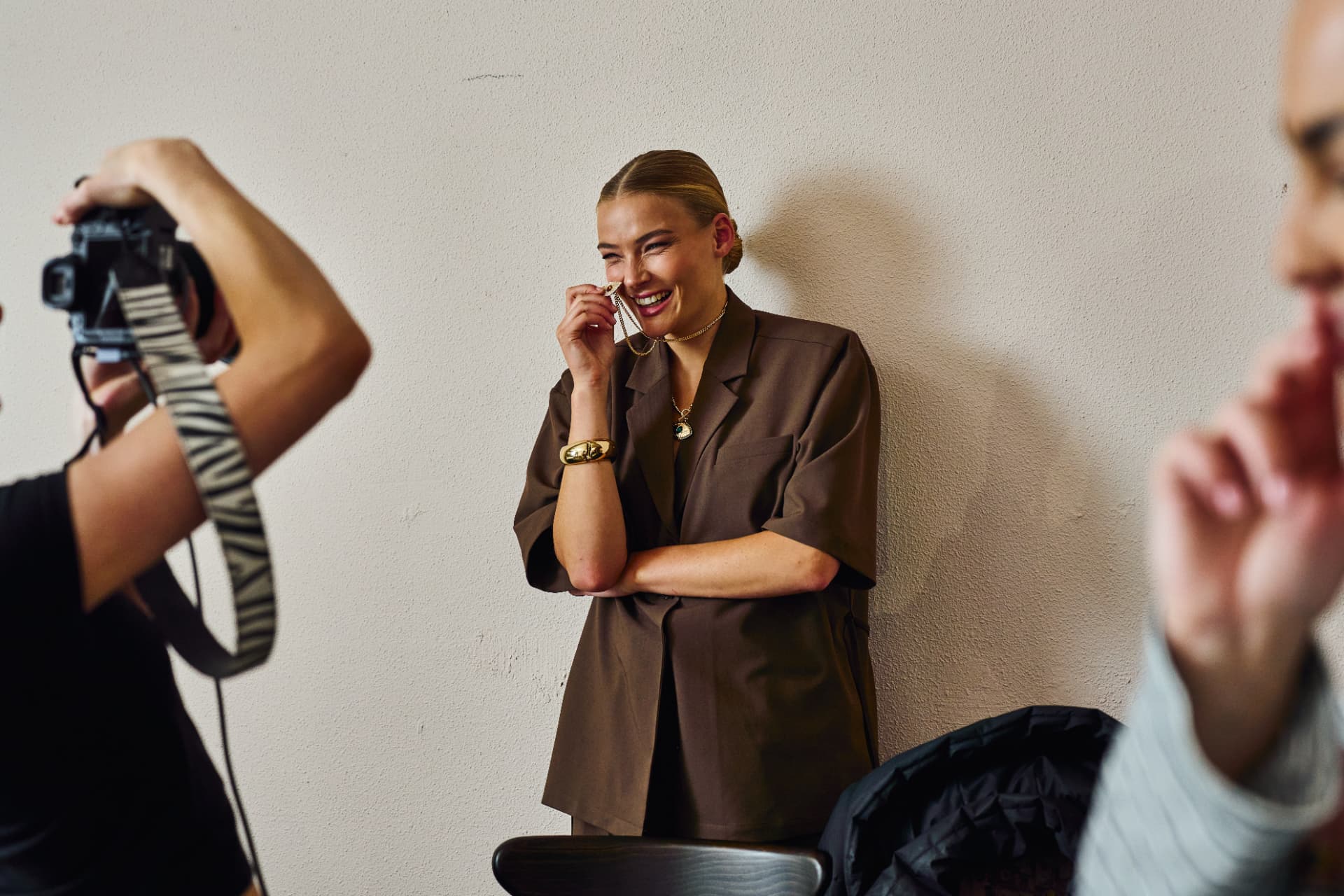 Model laughing in brown tailoring while being photographed