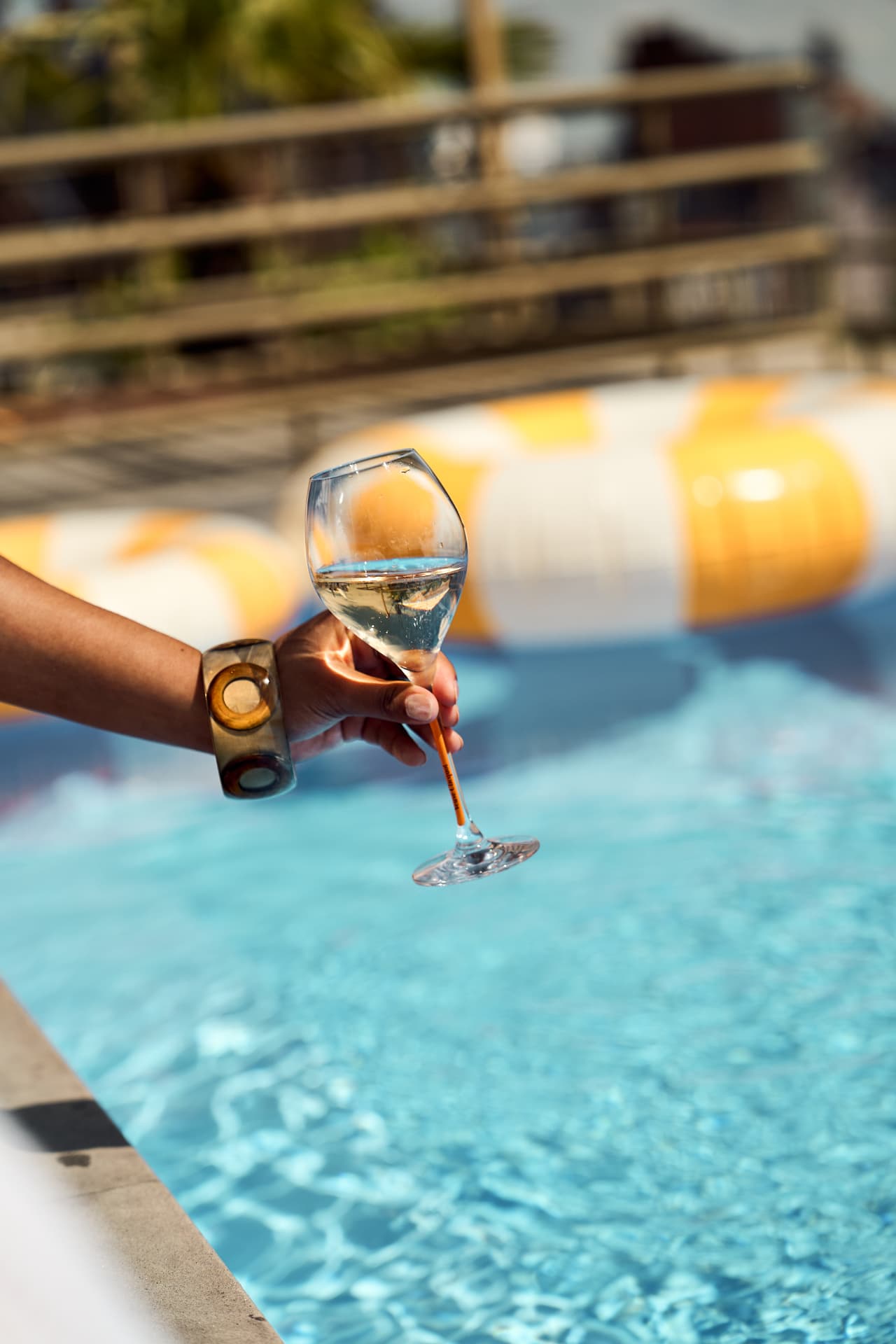 Hand holding a glass over the pool