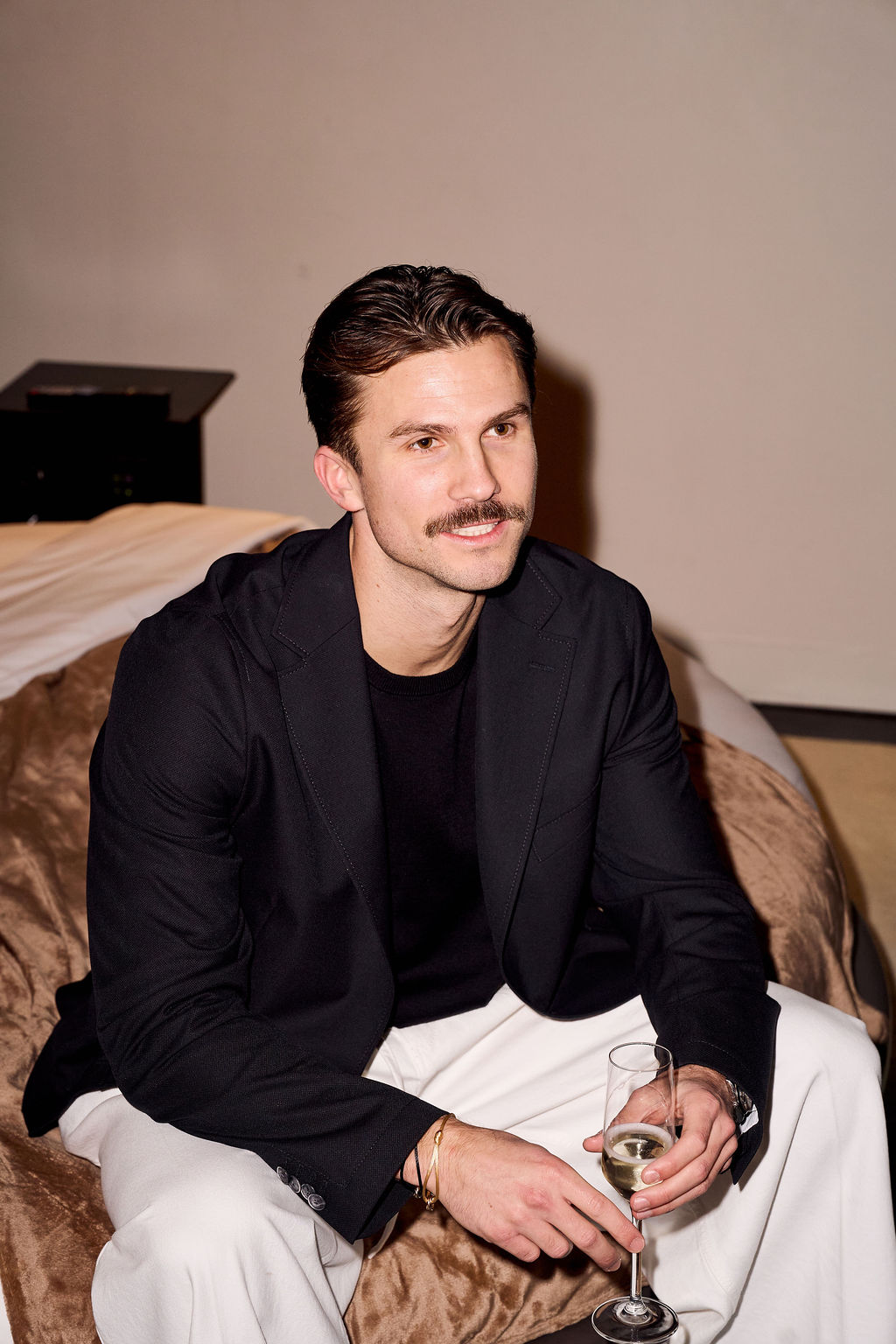 Guest in a black blazer seated on the hotel bed