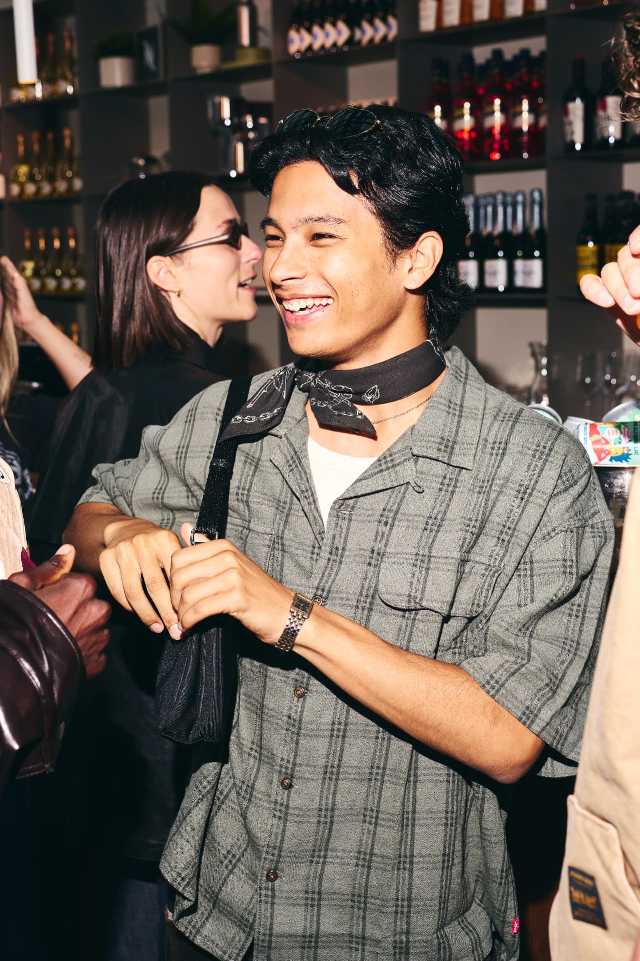 Guest laughing in a checked shirt and bandana at the bar