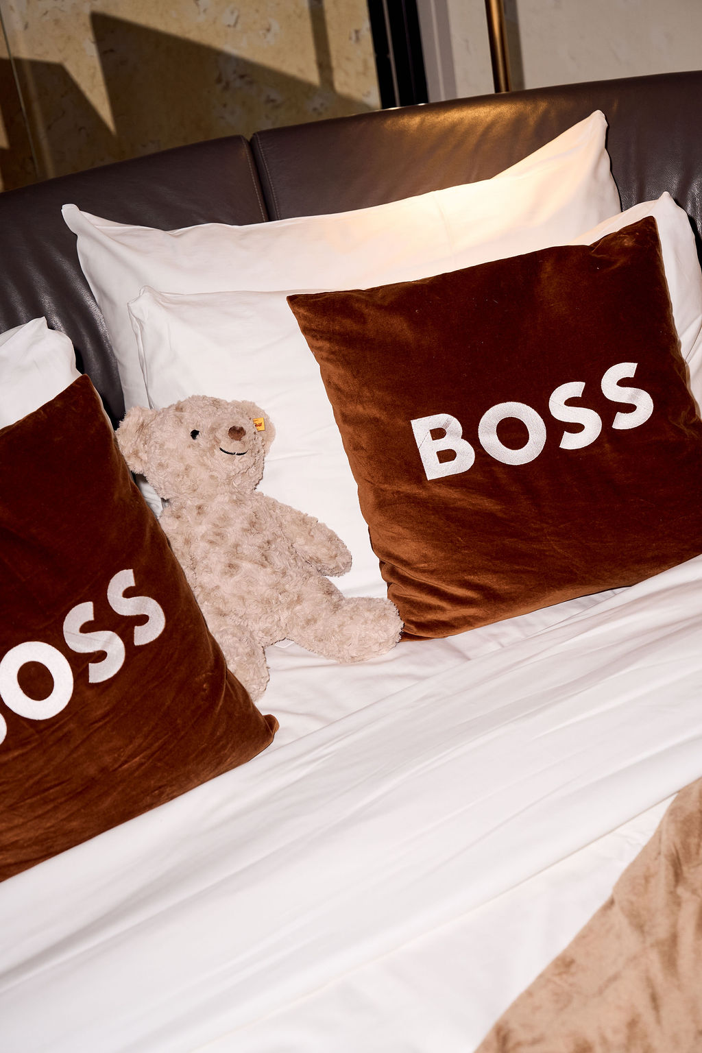BOSS velvet pillows and a teddy bear on the bed